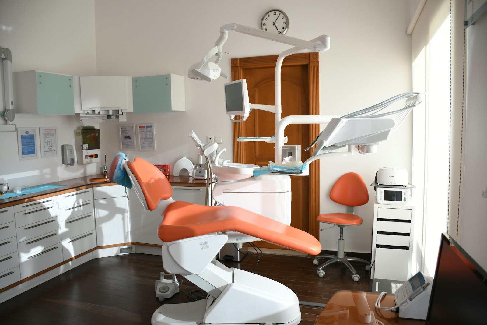 A dental treatment room with an orange chair