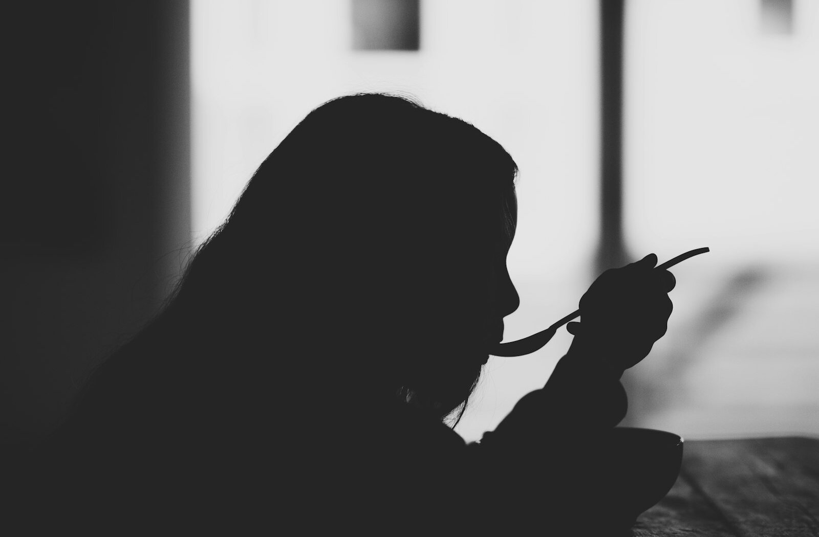 Side silhouette of a person eating with a spoon