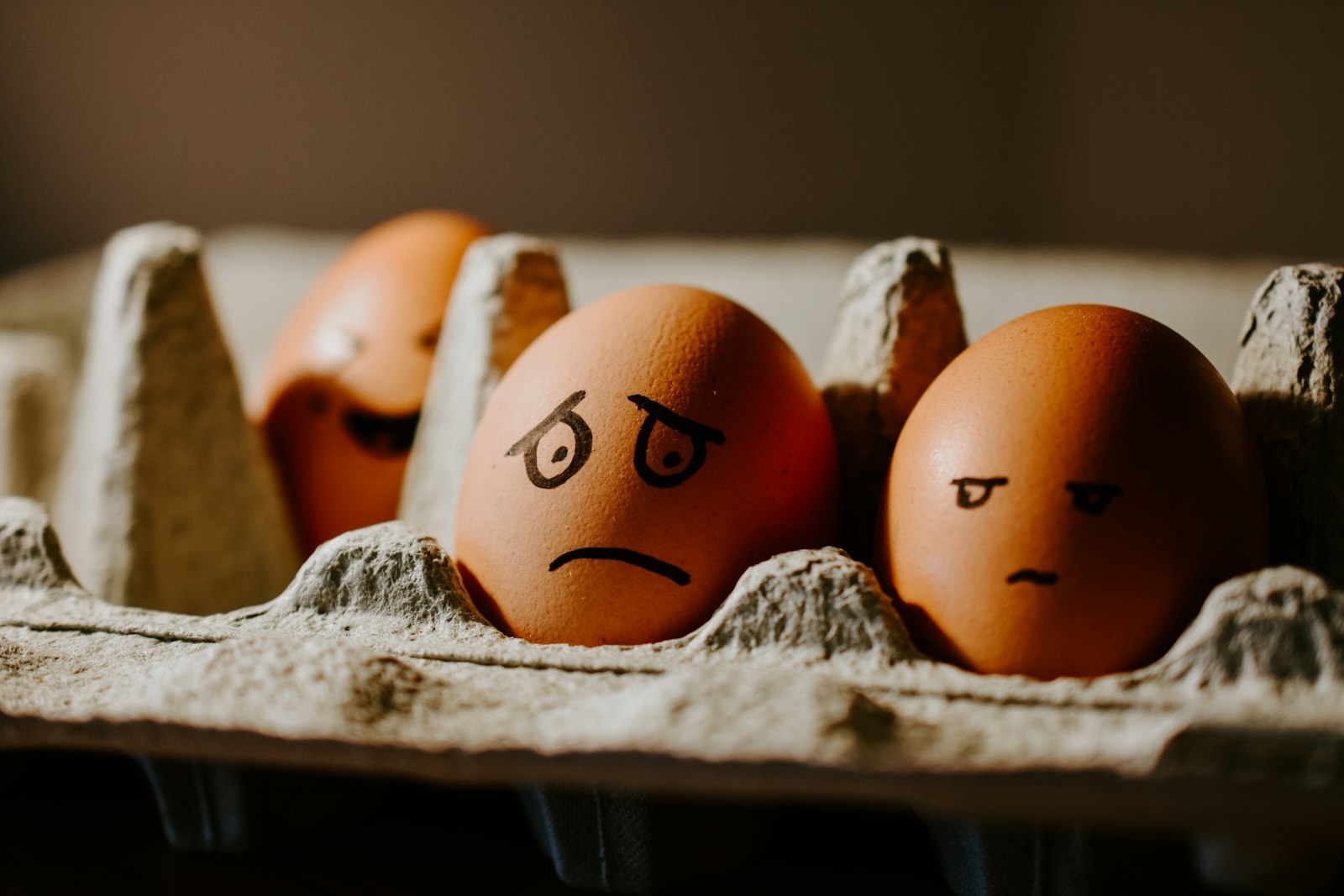 Eggs with faces drawn on them, sitting in an egg carton