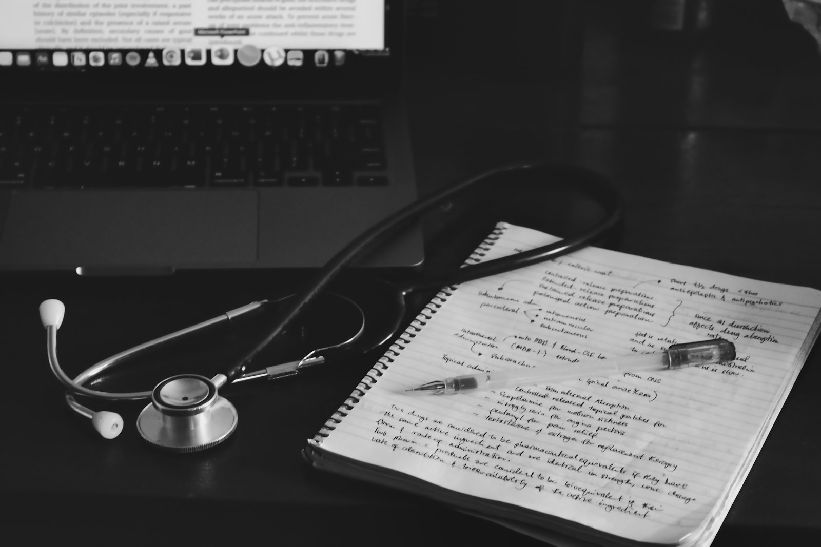 A stethoscope and a notebook beside a laptop