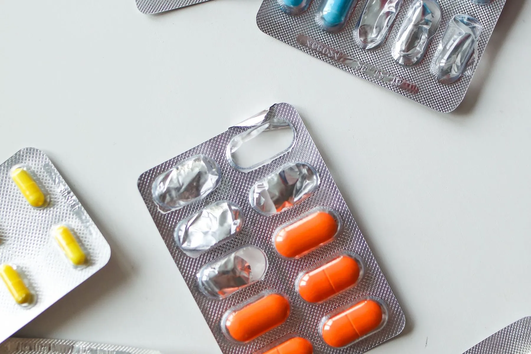 Assorted blister packs of tablets and capsules laid out on a white table