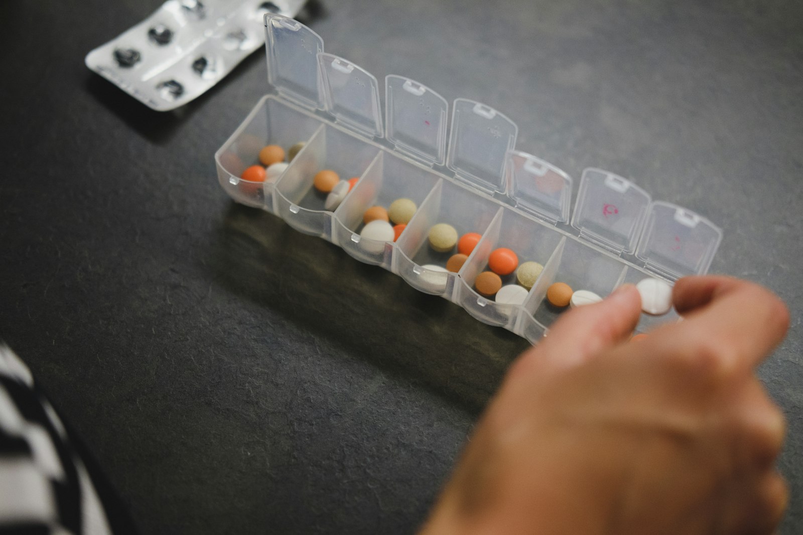 A weekly pill organiser held in one hand