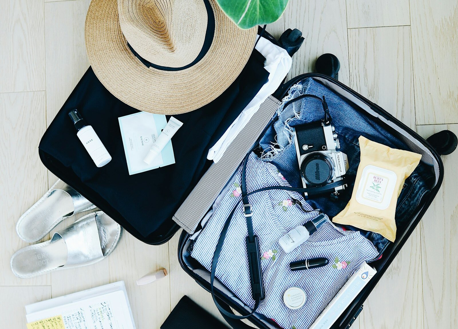 A suitcase packed for travel with a hat and a camera