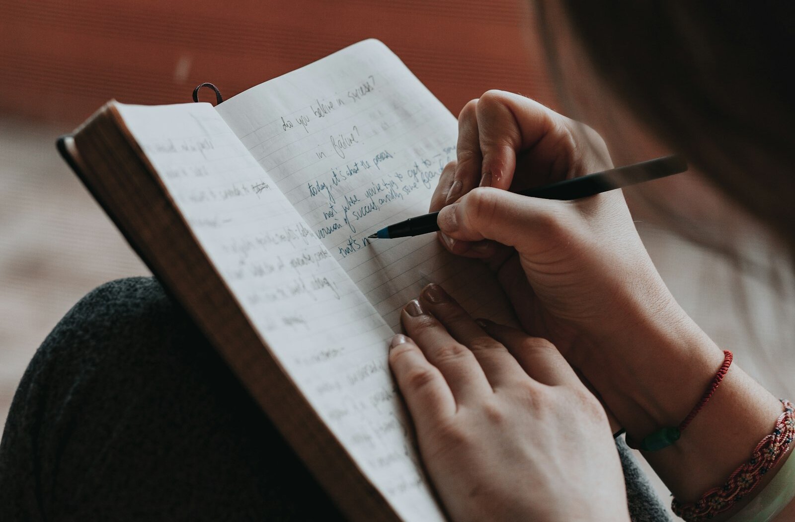 A hand writing in a notebook with a pen