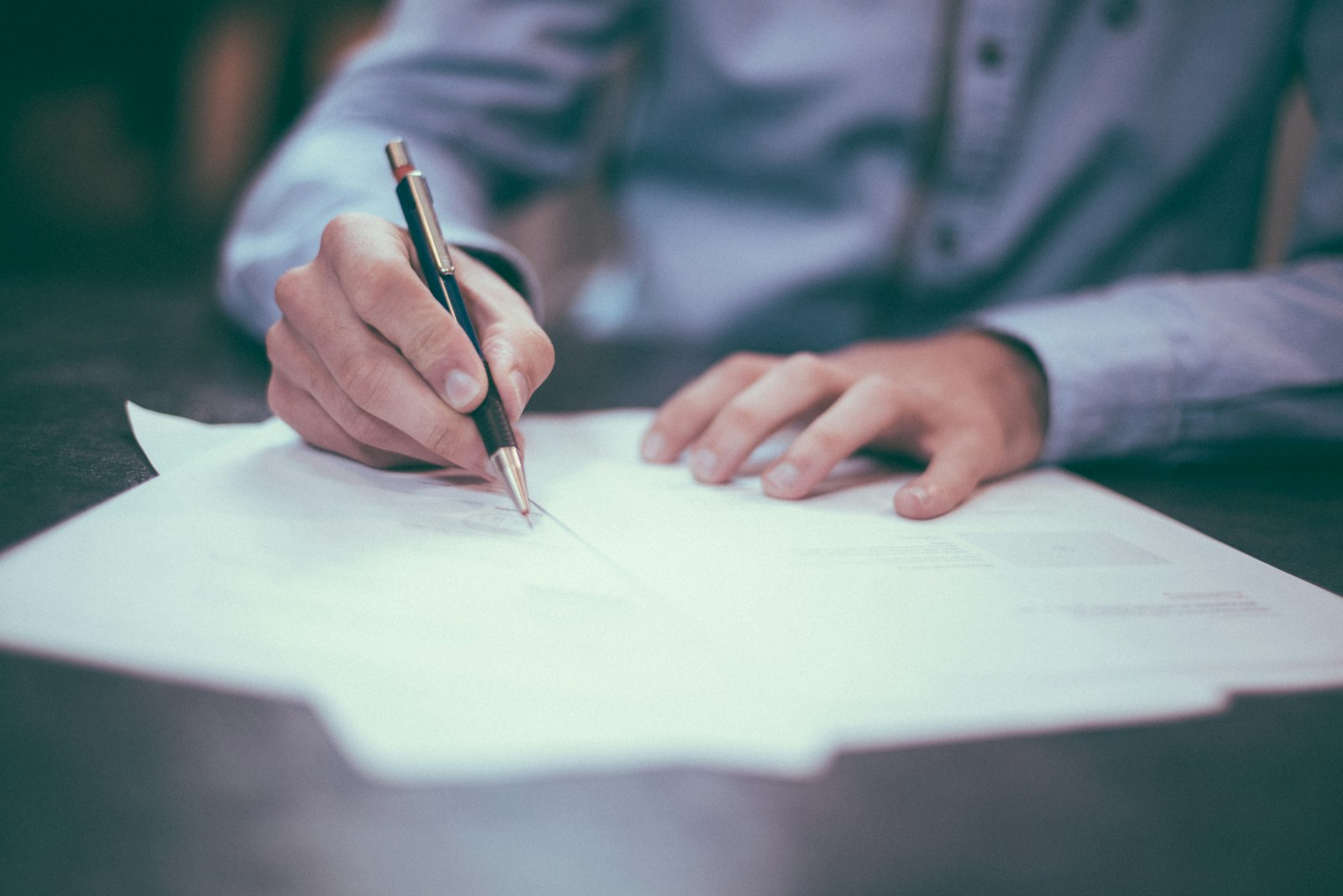 A person's hands signing a document with a pen